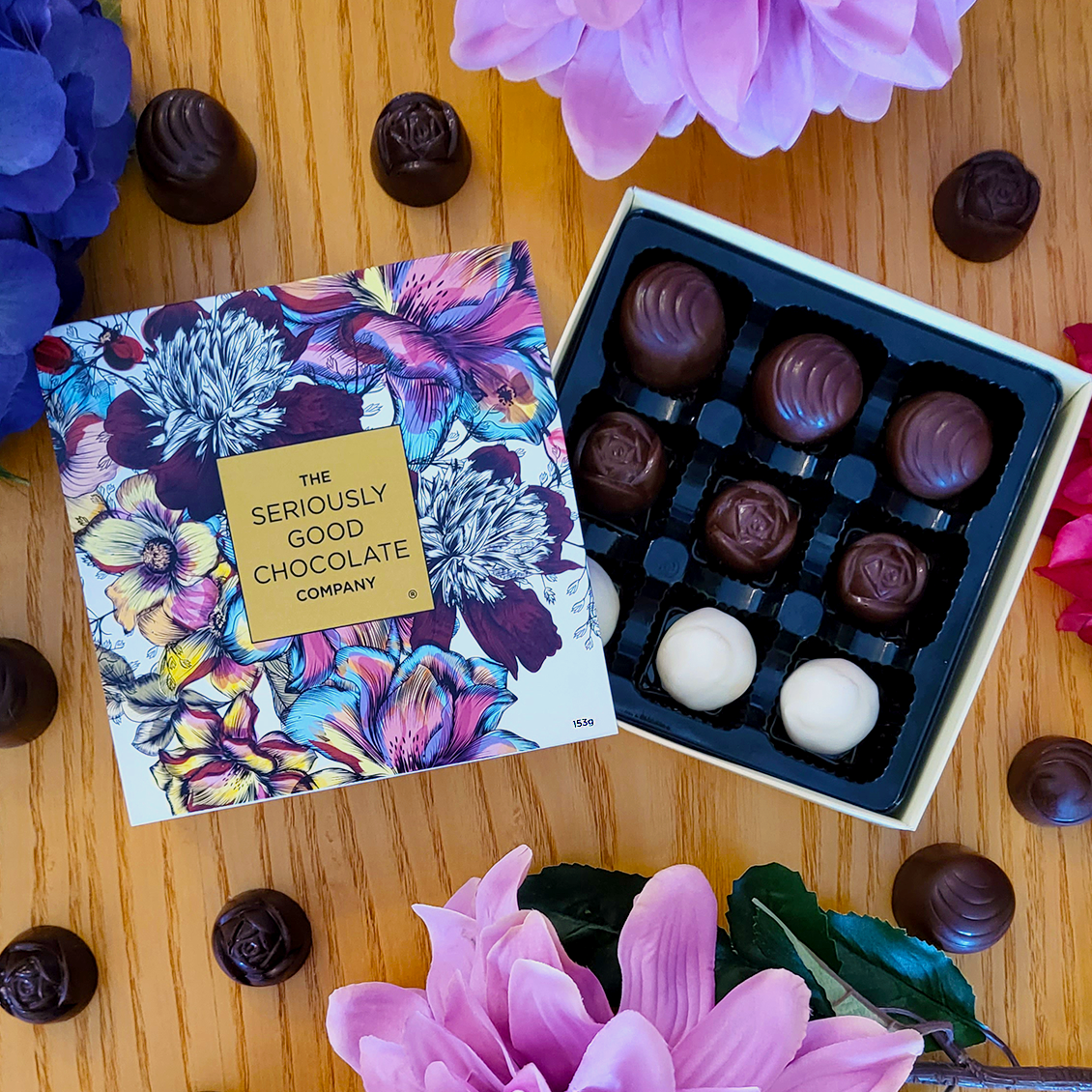 Open Box of The Seriously Good Chocolate Company 9 Piece Indulgent Artisan Chocolates Botanica Collection Handmade in Southland NZ decorated with blue, pink & red flowers plus chocolates
