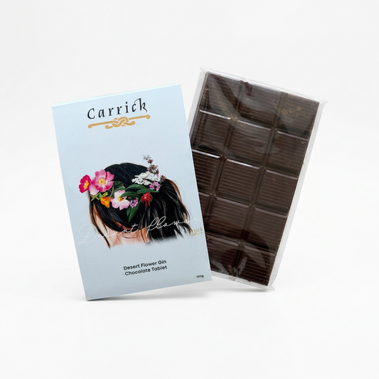 A packaged chocolate bar set from Carrick, featuring a light blue illustrated card labeled 'Desert Flower Gin Chocolate Tablet' and a clear plastic sleeve around a dark brown segmented chocolate bar, photographed on a clean white background.