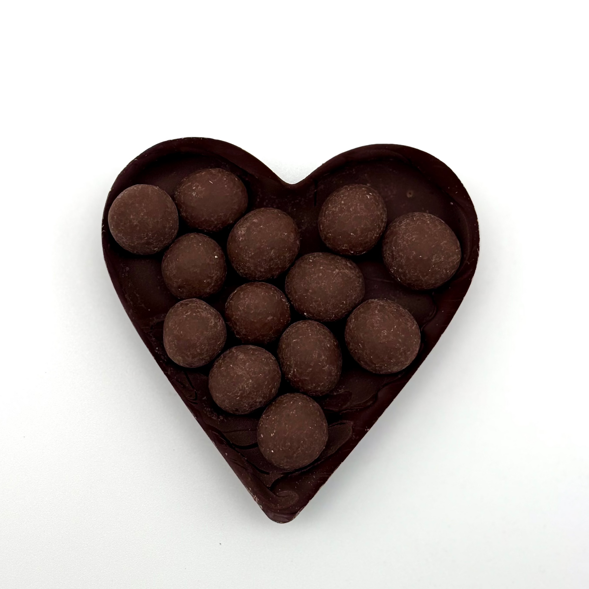 Heart-shaped chocolate mold filled with chocolate truffles on a white background