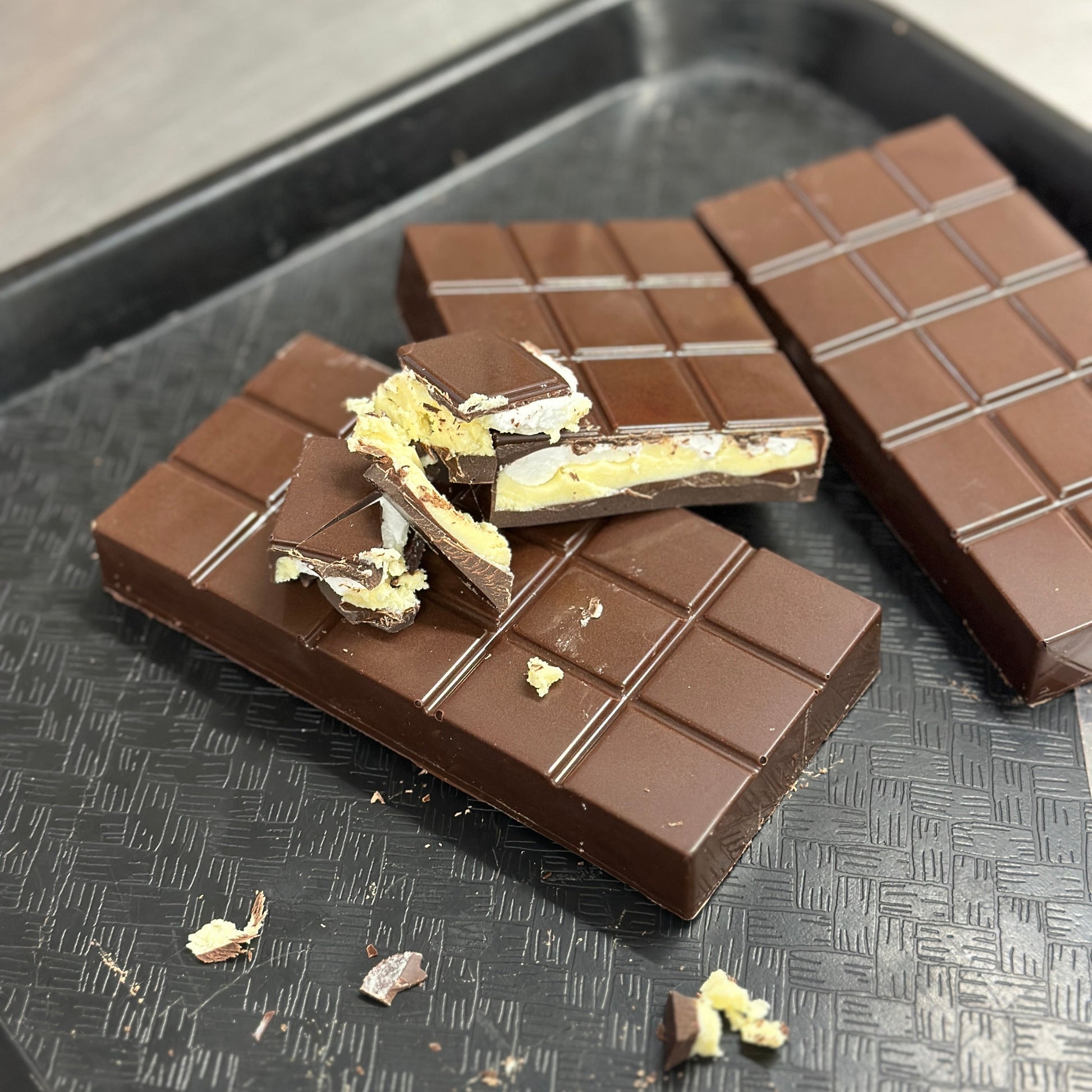 Chocolate bars with lemon meringue filling on a dark tray