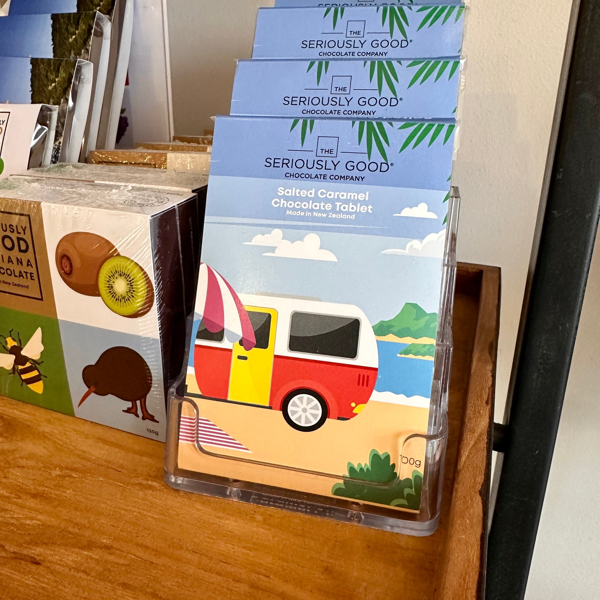 Packaging of ' Seriously Good' brand salted caramel chocolate tablet. The packaging features a colorful illustration of a retro caravan with a beach and trees in the background.