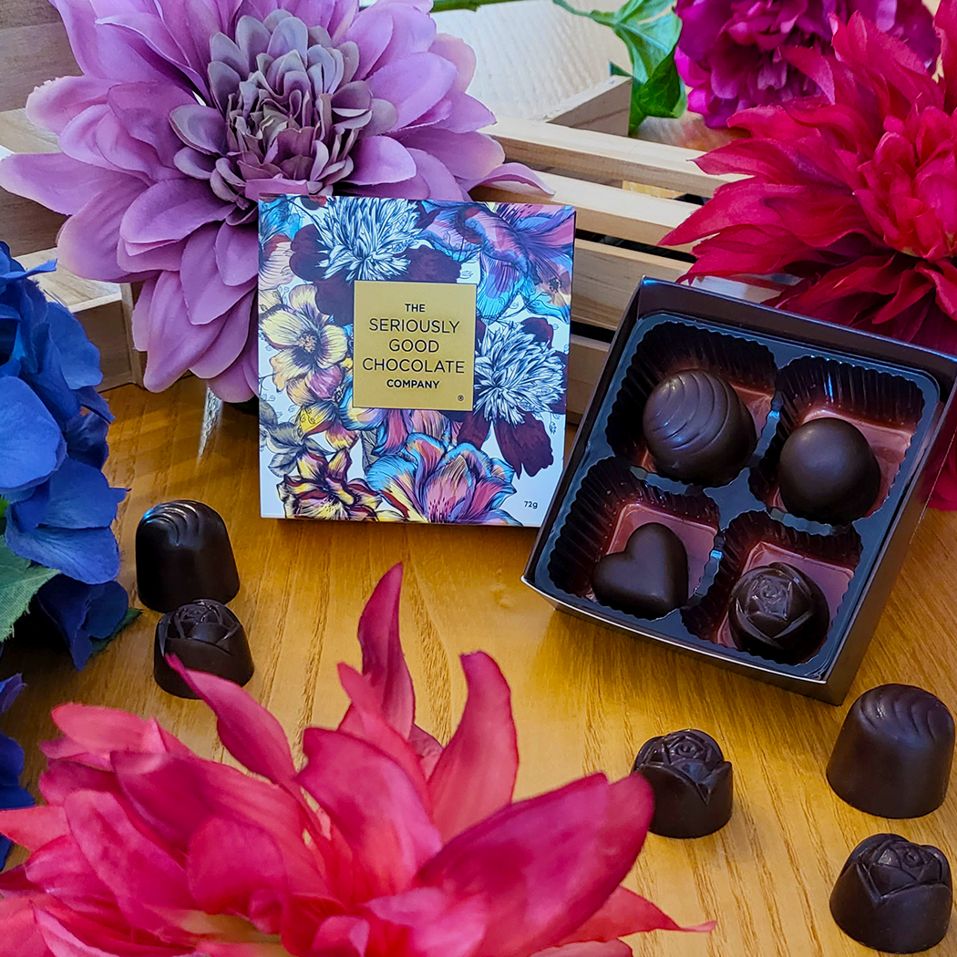 Open Box beside standing box of The Seriously Good Chocolate Company 4 Piece Indulgent Artisan Chocolates Botanica Collection Handmade in Southland NZ decorated with blue, pink & red flowers plus chocolates