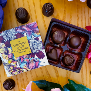 Open Box of The Seriously Good Chocolate Company 4 Piece Indulgent Artisan Chocolates Botanica Collection Handmade in Southland NZ decorated with blue, purple & red flowers plus chocolates