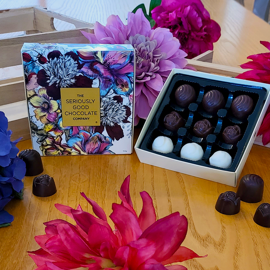 Open Box beside standing box of The Seriously Good Chocolate Company 9 Piece Indulgent Artisan Chocolates Botanica Collection Handmade in Southland NZ decorated with blue, pink & red flowers plus chocolates